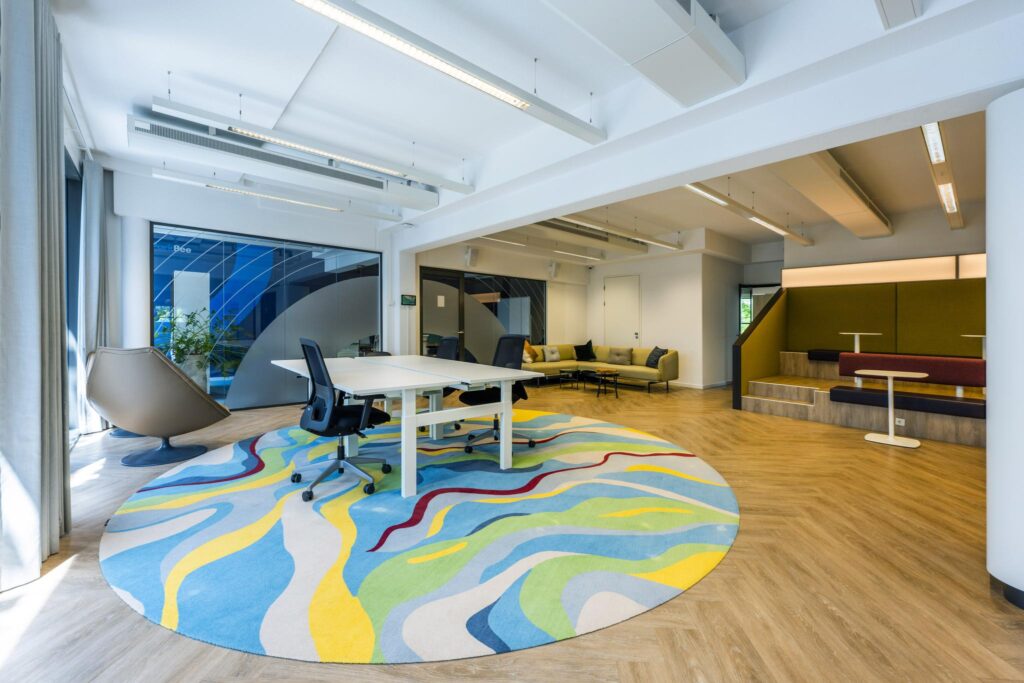 Modern office space on Mr. Treublaan with colorful round rug, open seating areas, and natural light.